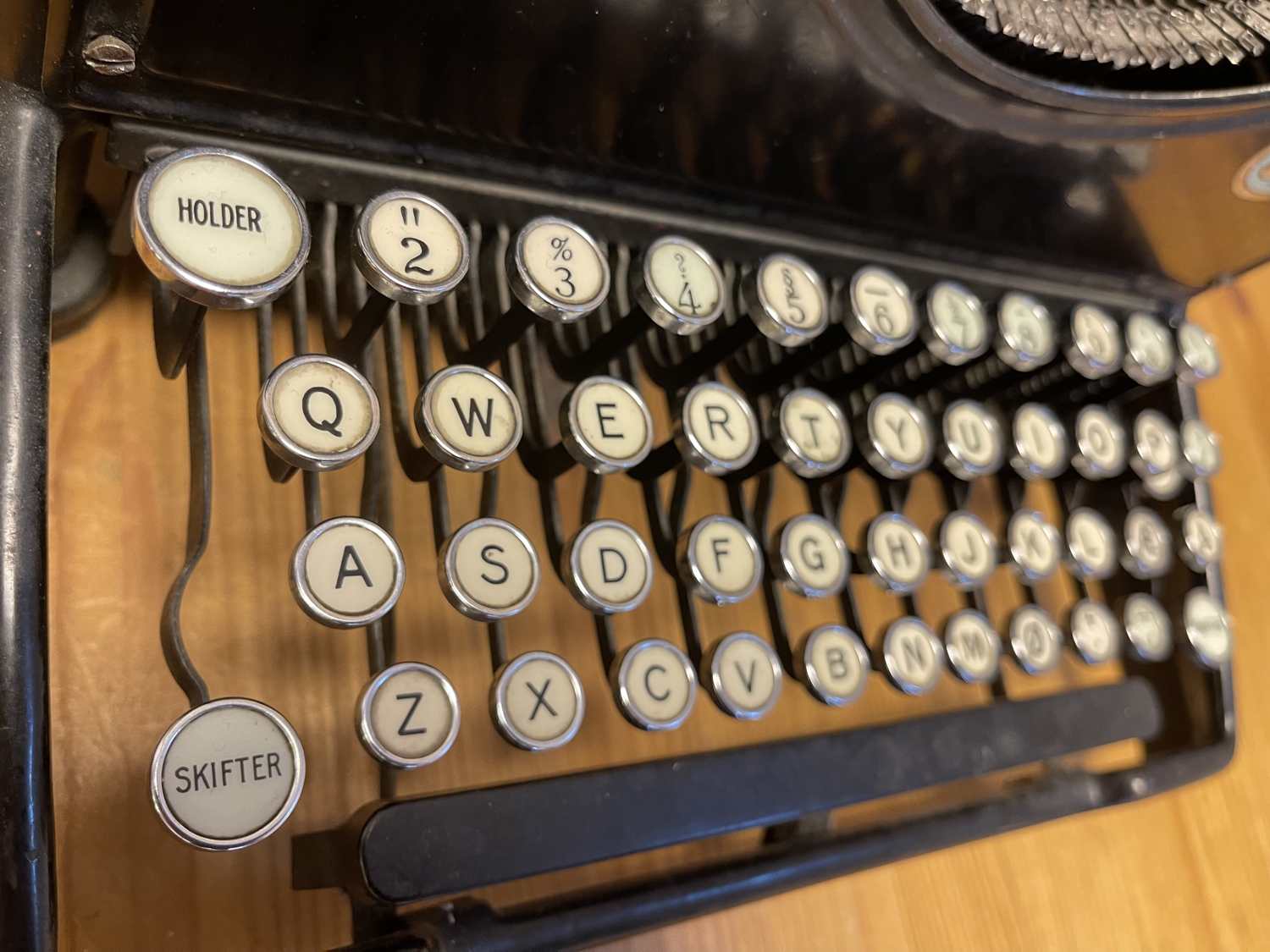 Clavier QWERTY d'une ancienne machine à écrire, aux touches rondes, présentant chaque caractère en noir sur fond blanc